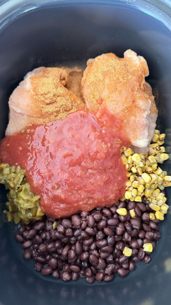 raw chicken, corn, beans, green chilies, tomatoes and seasonings in base of crock pot, uncooked