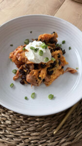 A white plate with a serving of slow cooker chicken enchilada casserole