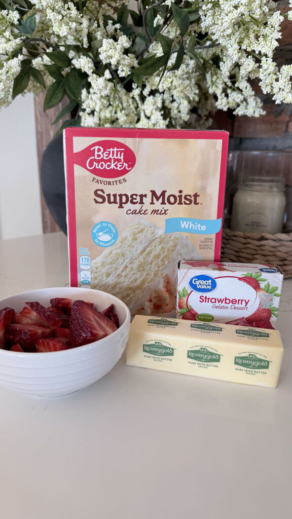 Strawberry dump cake ingredients on white counter with flowers in background