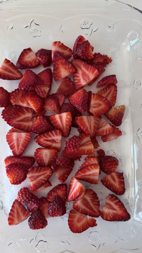 Sliced strawberries at bottom of clear baking dish