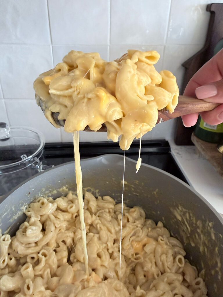 cooked creamy mac and cheese on a spoon coming out of pot of creamy mac and cheese