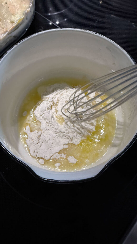 flour mixed into melted butter on stove, with whisk
