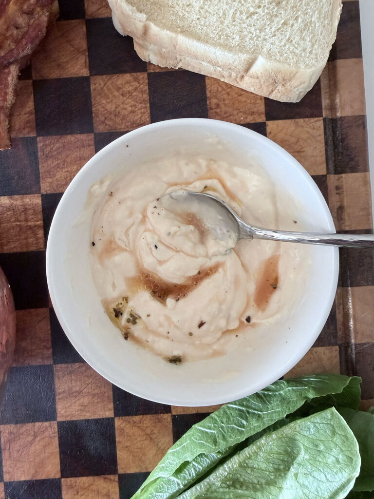 mayonnaise, vinegar, and seasonings in white bowl on cutting board