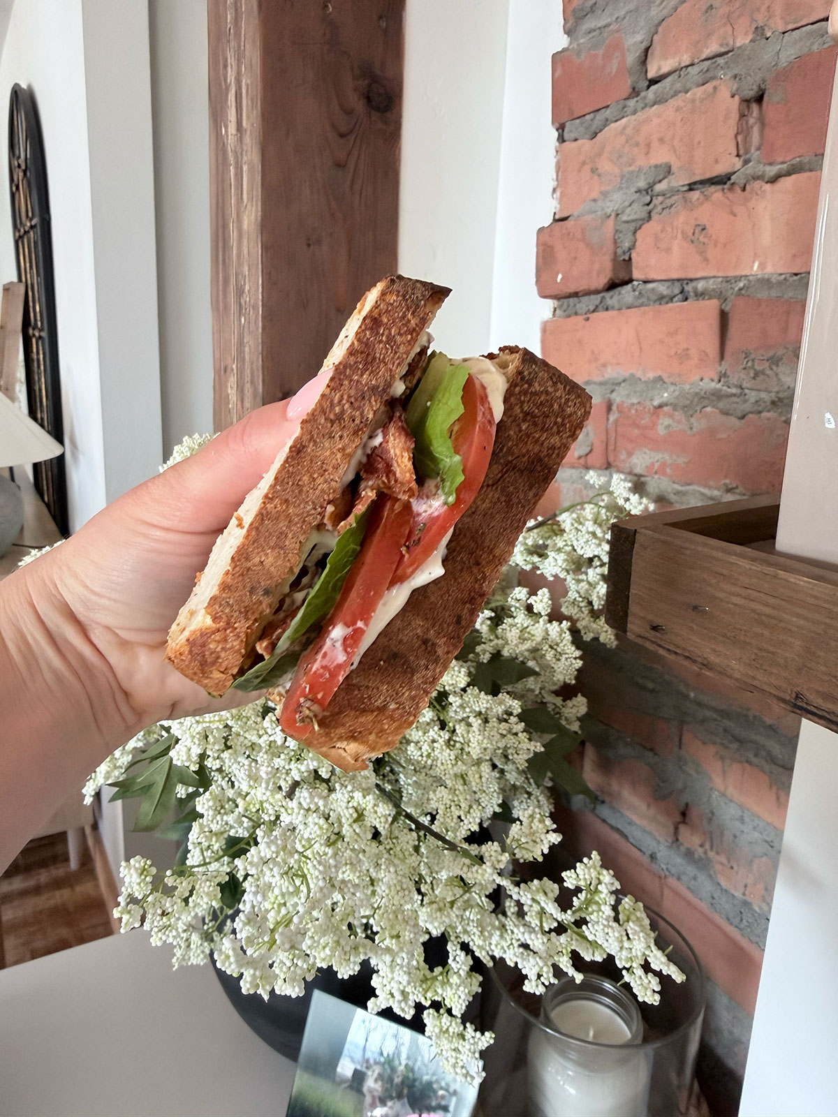 side view of blt sandwich with hand holding it
