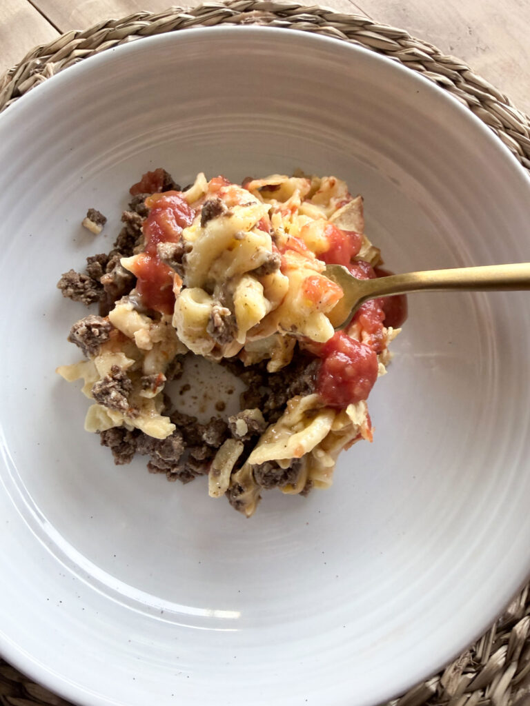 mac and cheese taco bake in white bowl on placemat with gold fork
