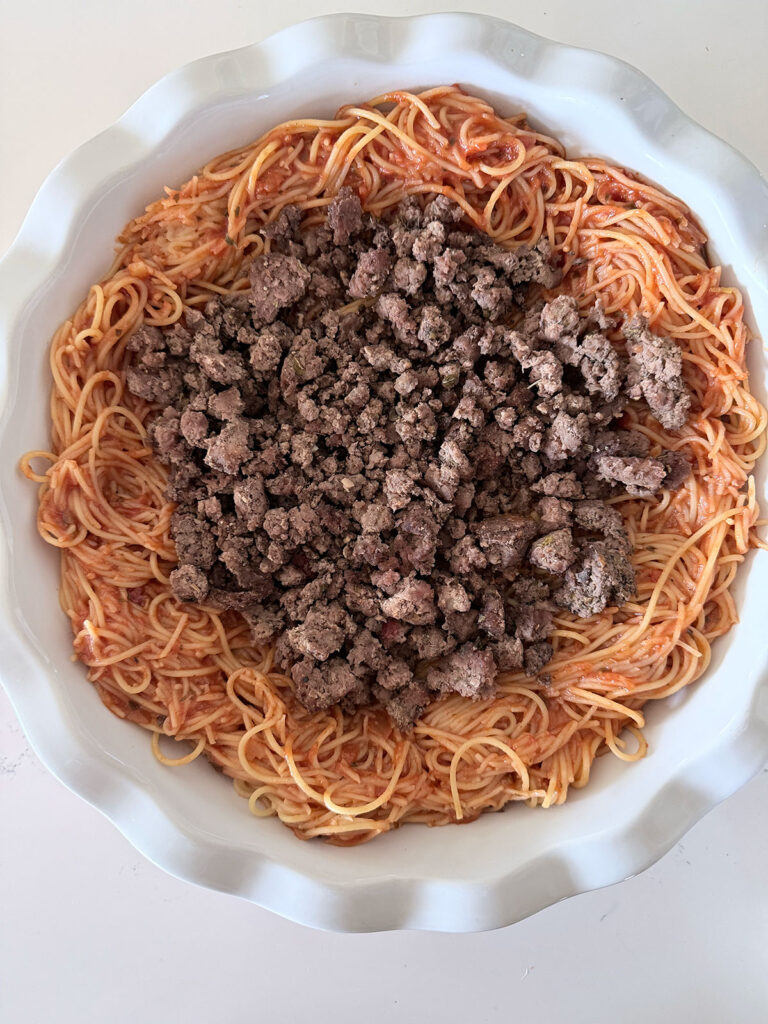 spaghetti in pie dish topped with ground beef