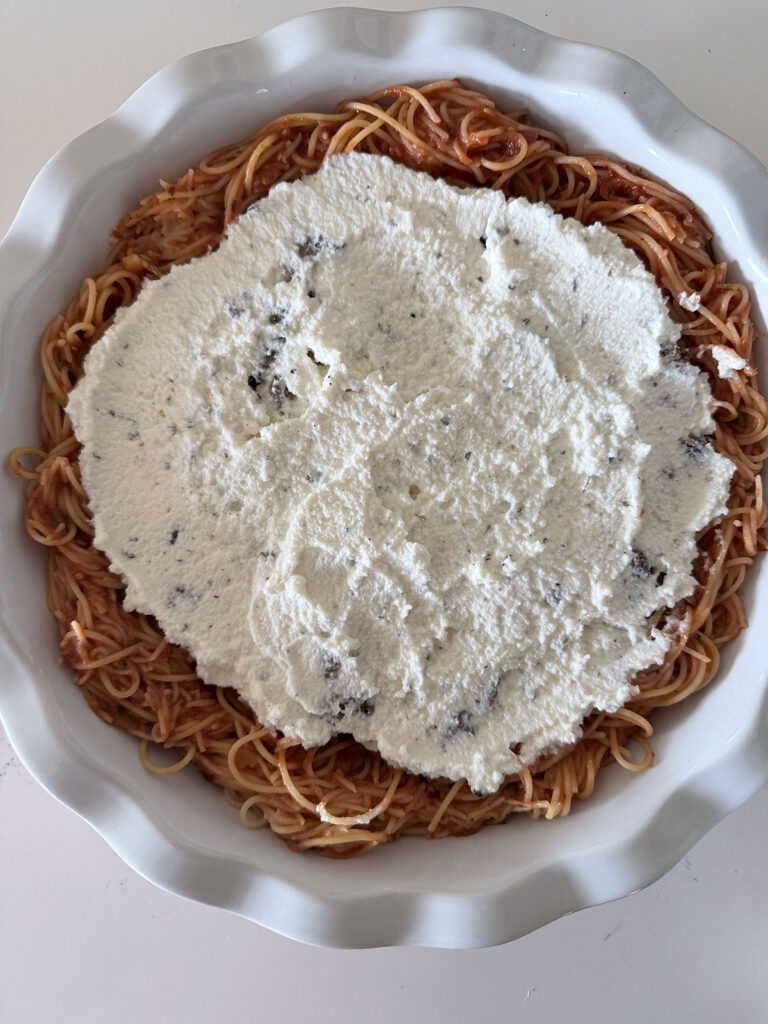spaghetti pie topped with ricotta mixture