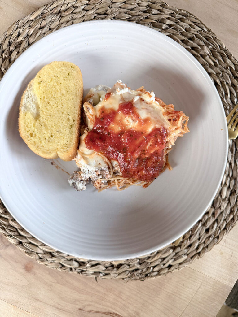 serving of spaghetti pie with bread on white plate