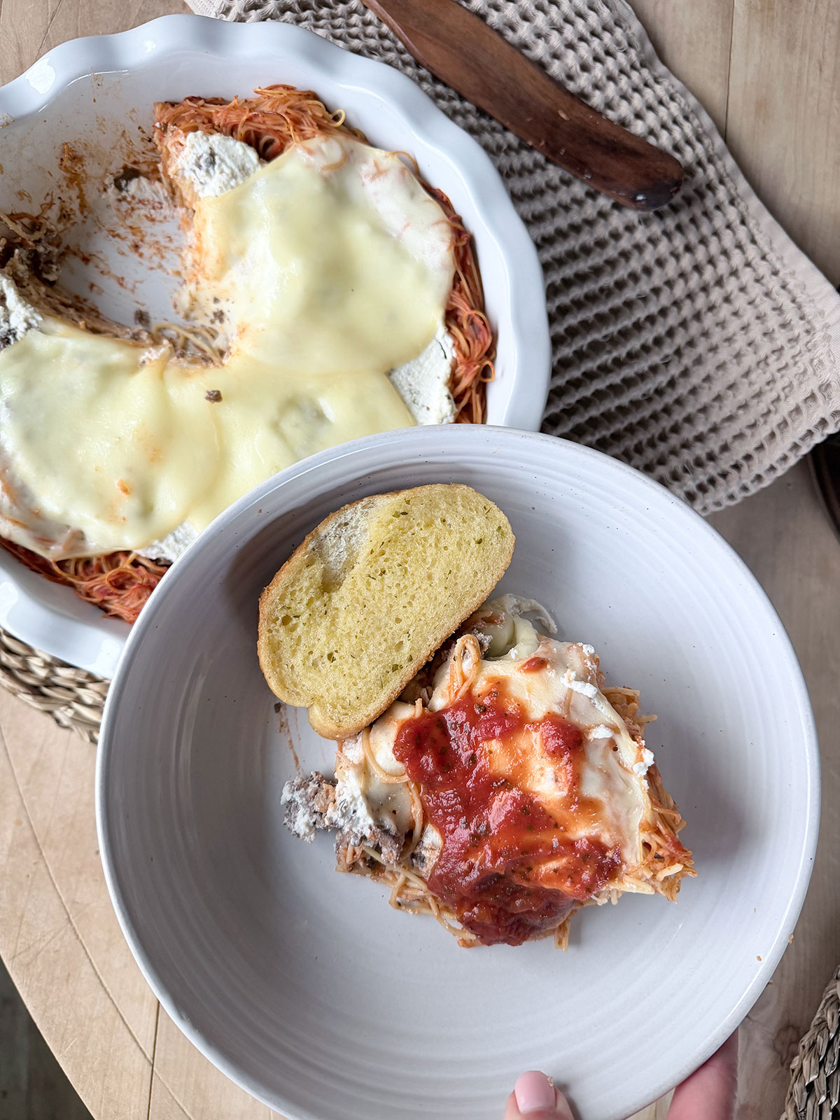 Spaghetti pie with a slice removed, and serving of spaghetti pie with bread in white bowl
