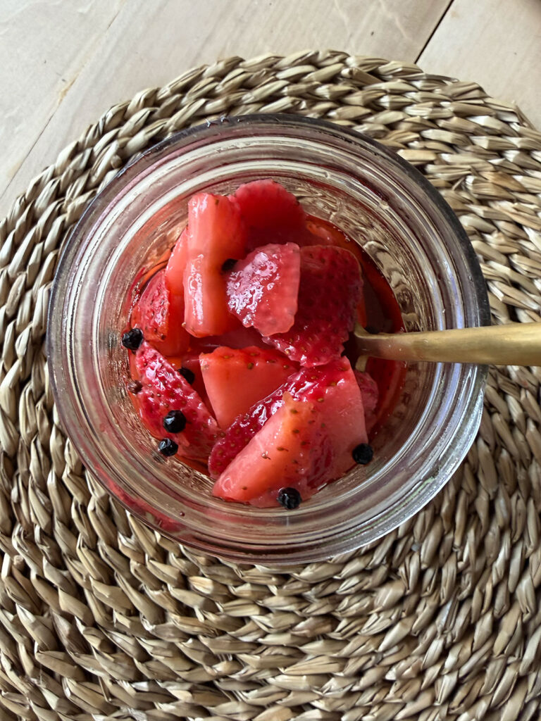 pickled strawberries in glass jar with gold utensil