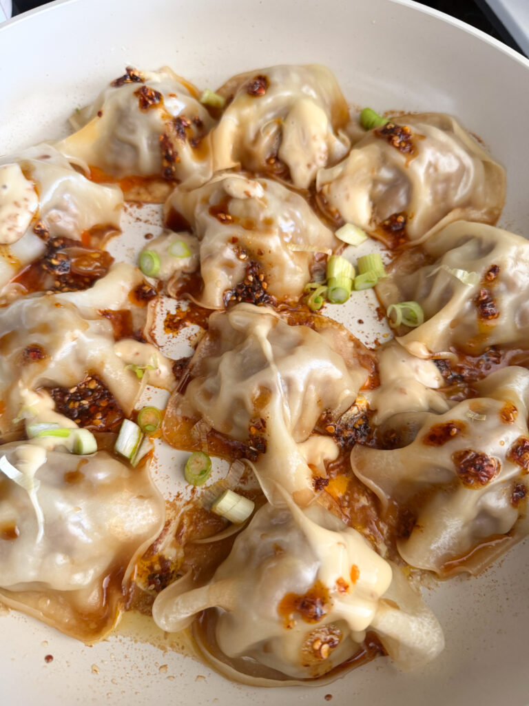 steamed dumplings with soy sauce, green onion, chili oil and miso mayo on top.