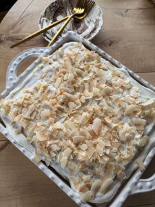 coconut poke cake topped with toasted coconut flakes
