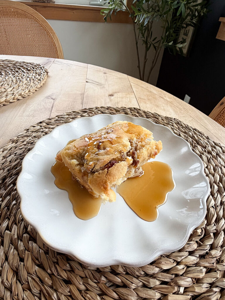 A white plate with pancake sausage casserole with syrup.
