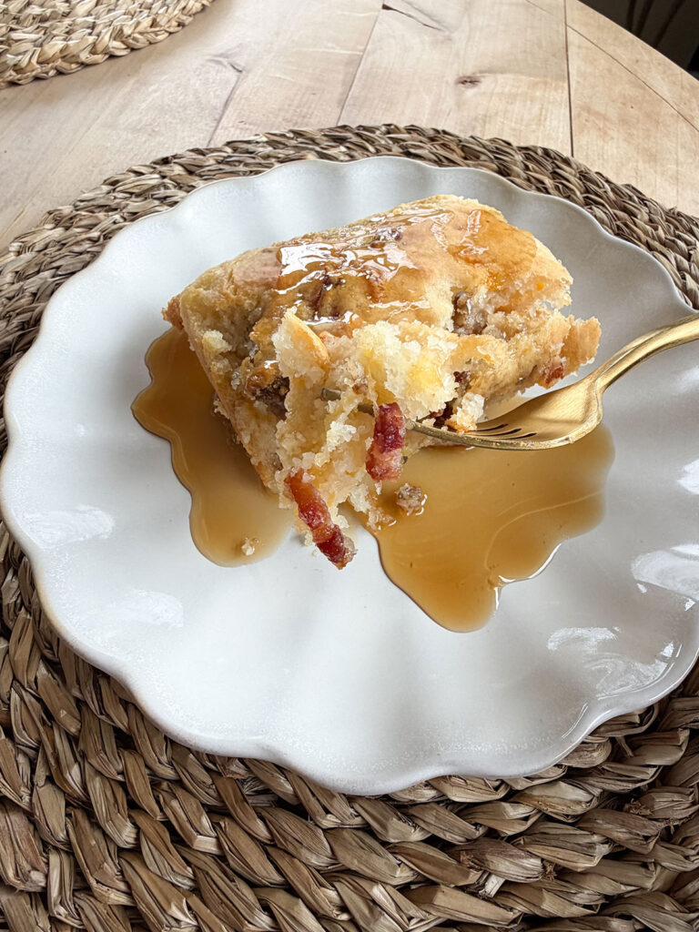 A white plate with pancake sausage casserole on a white plate with a gold fork.