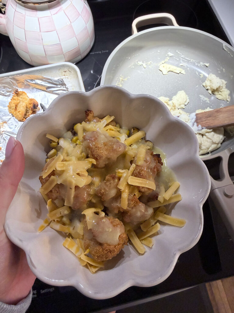 KFC bowl in white bowl. chicken and mashed potatoes on stovetop in background.