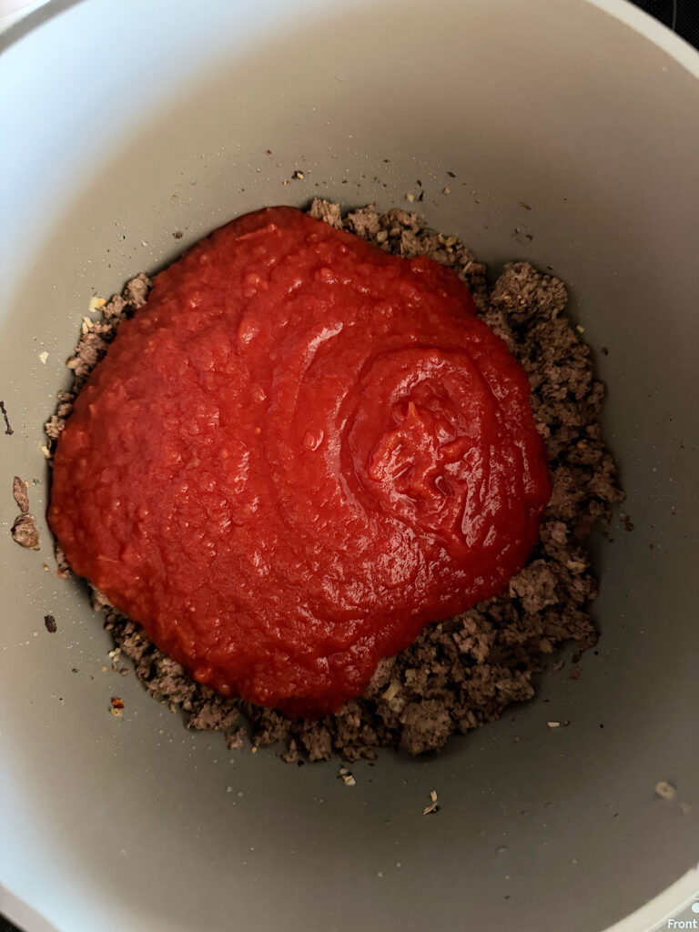 ground beef and canned tomatoes in pot