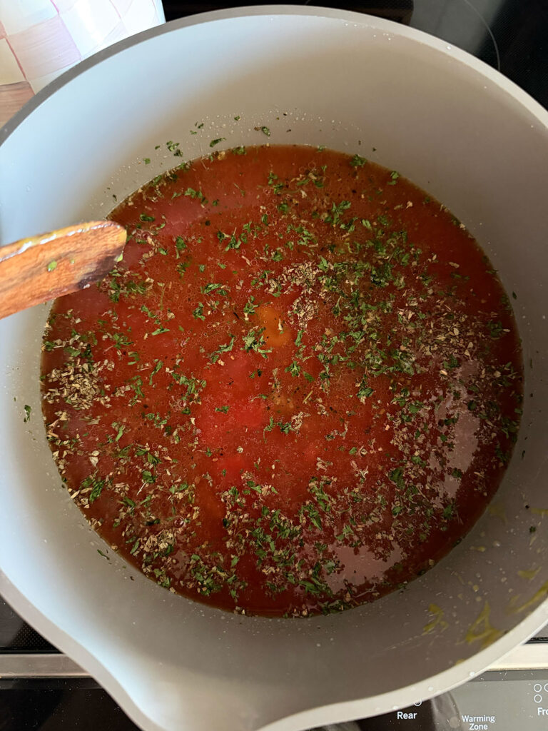 beefy tomato soup in pot with dried herbs