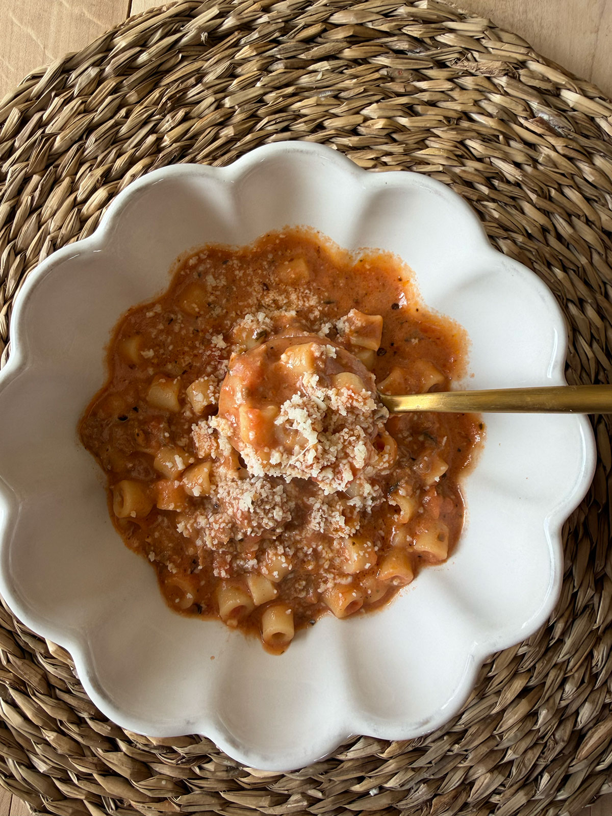beefy tomato soup in white scalloped bowl with gold spoon on placemat