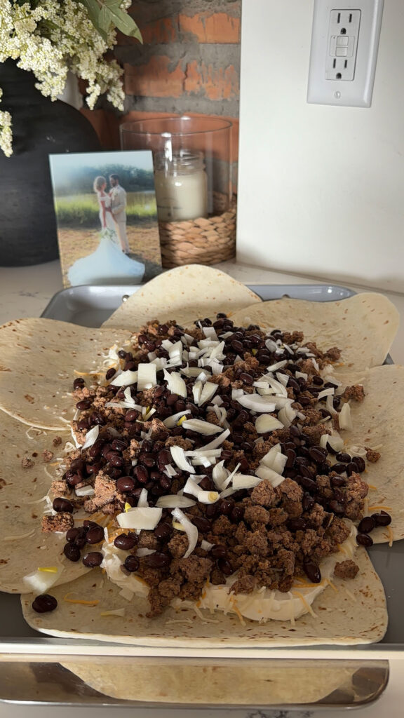 sheet pan quesadilla being built on sheet pan with meat and fillings