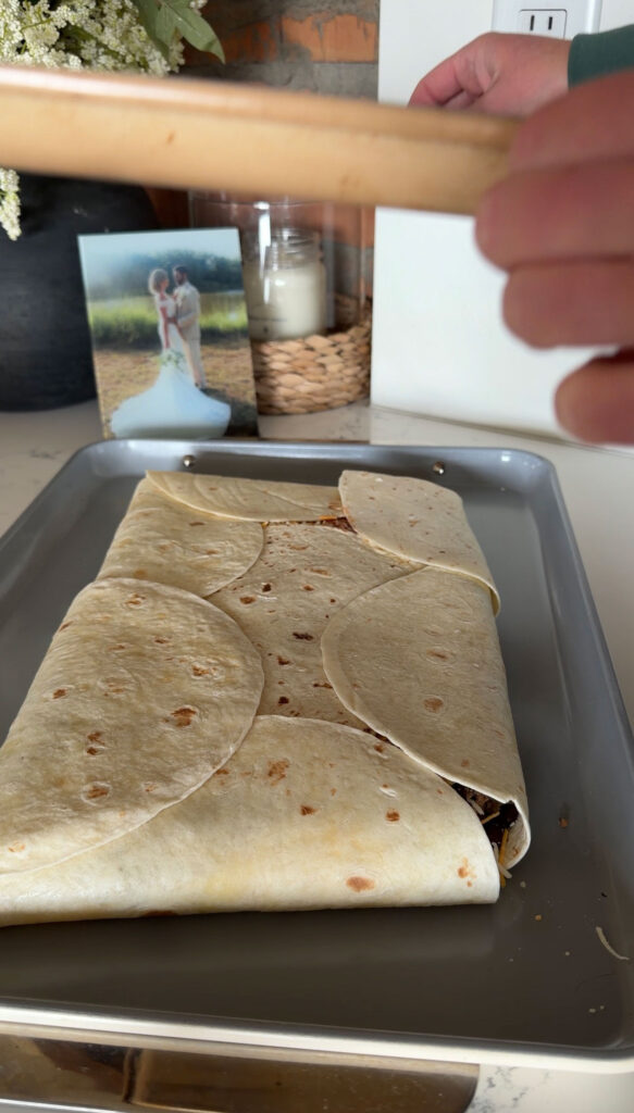 folded quesadilla on sheet pan with another sheet pan overtop, ready to press down