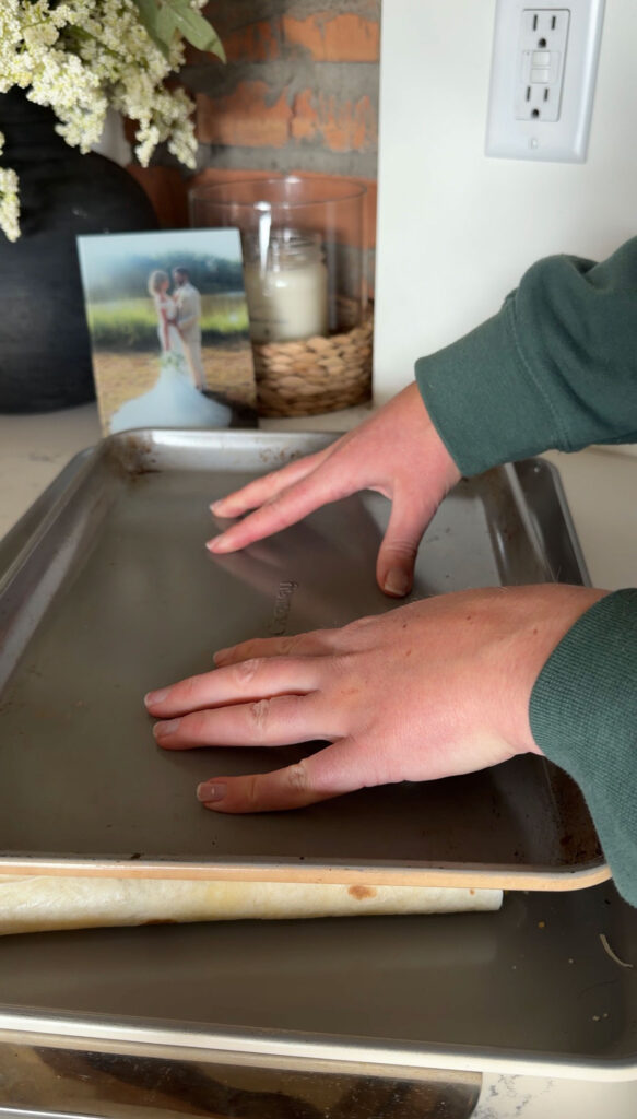 Hands sandwiching the quesadilla in between two sheet pans