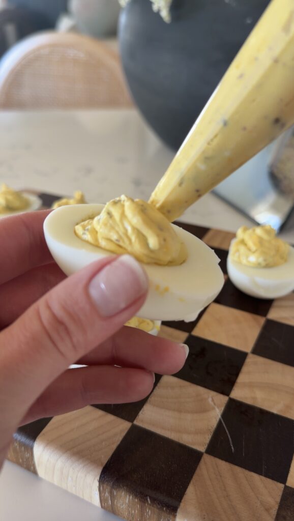 using a piping bag and filling the egg.