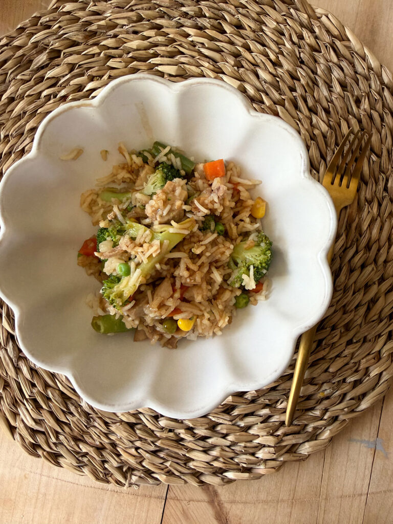 serving of chicken teriyaki casserole in white bowl on placemat with gold fork on the side