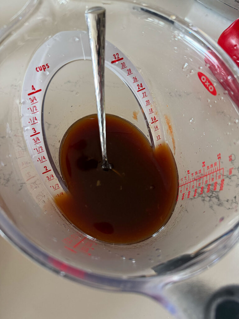 sweet and sour pork sauce in measuring cup with spoon