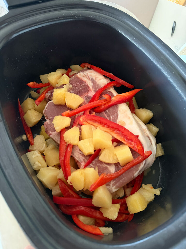 pork, pineapple and bell peppers in base of slow cooker