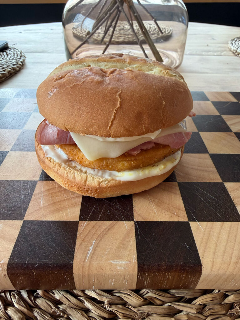 chicken cordon bleu sandwich on checkered cutting board, fully assembled, uncut