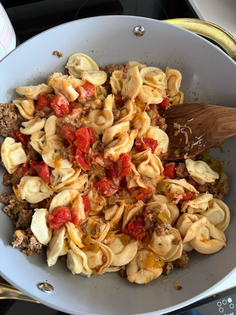 taco tortellini being mixed in pan with wooden spoon