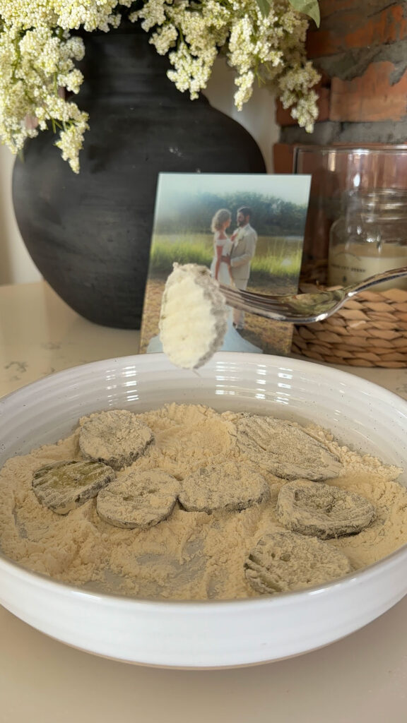 Dredging dill pickle slices in seasoned flour.