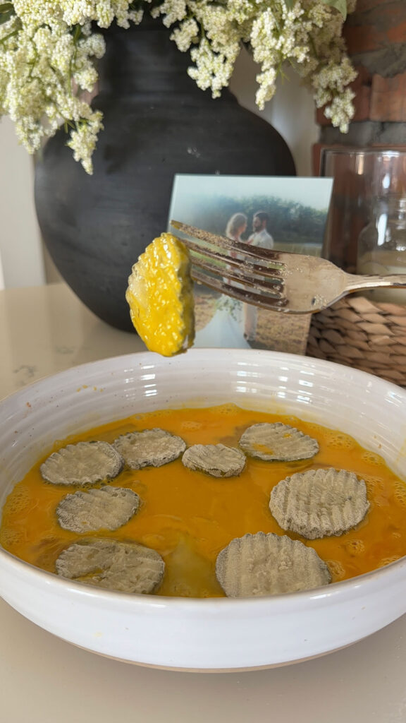 Dipping dill pickle slices in egg.