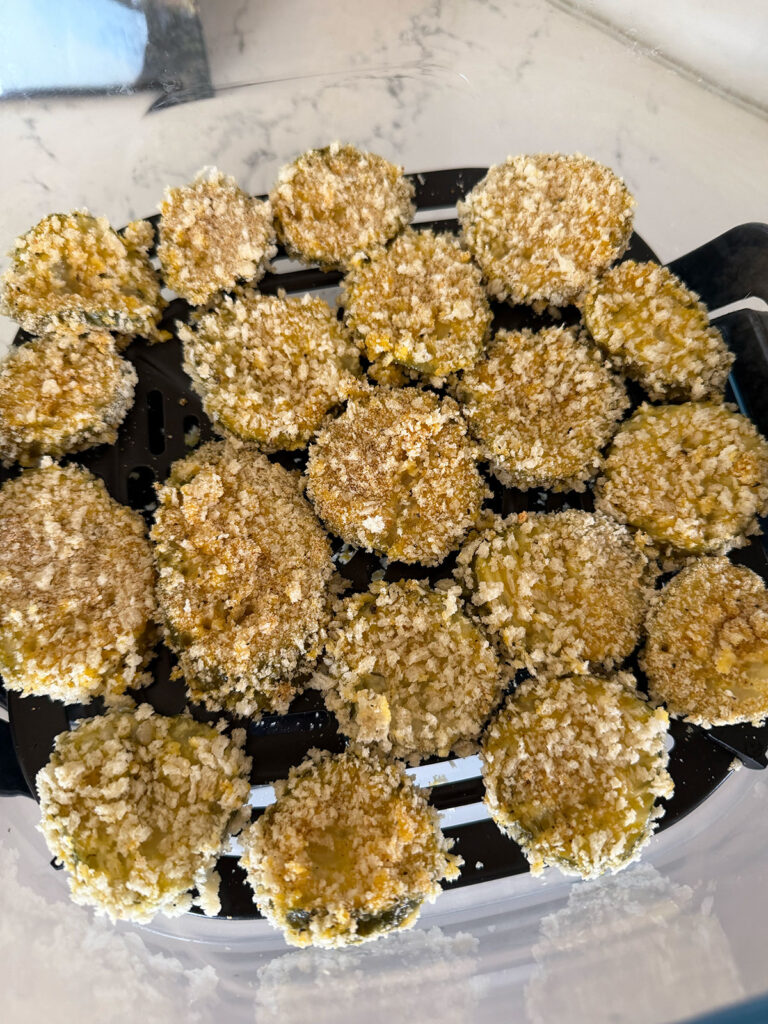 Dill pickle slices in an air fryer basket.