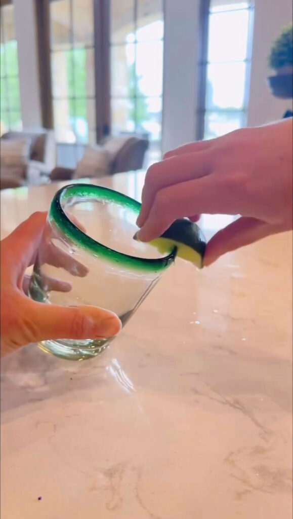 hand rubbing lime wedge on rim of glass