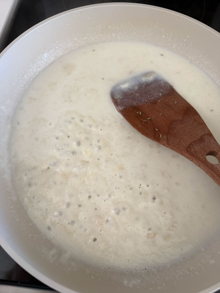 wooden spoon stirring butter, flour, milk (roux/bechamel) mix together in pot