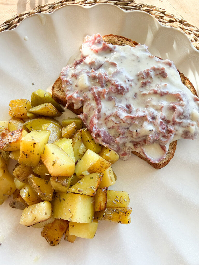 cream chipped beef on toast on white plate next to homefries