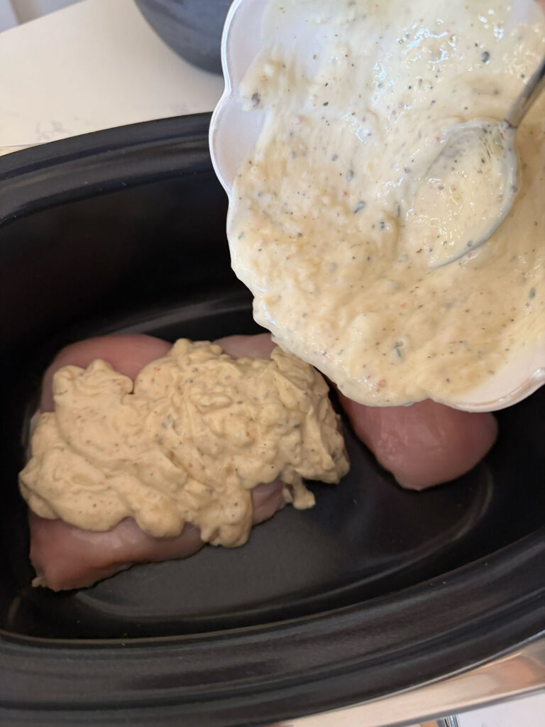 creamy mixture spooned over raw chicken breasts in base of slow cooker