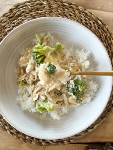 chicken divan over rice on white plate with gold forkful of chicken and broccoli