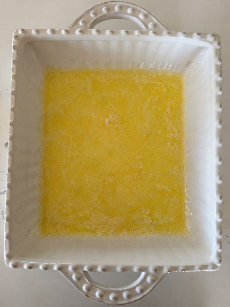 A white baking dish with melted butter.