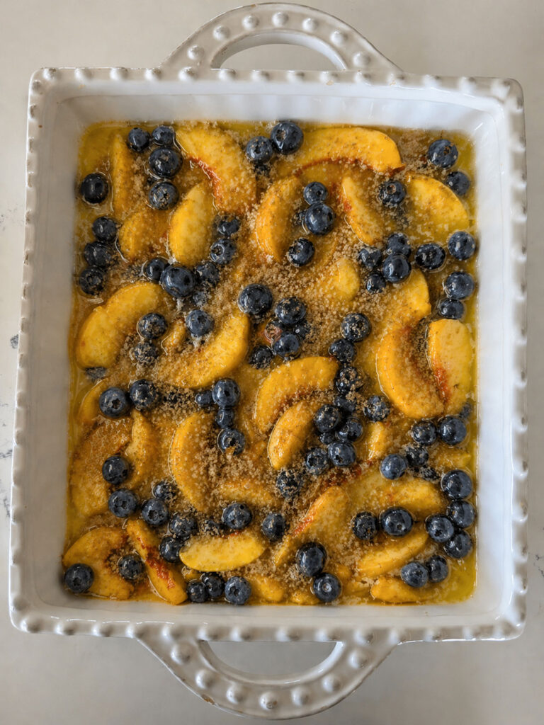 A white baking dish of peach blueberry cobbler.