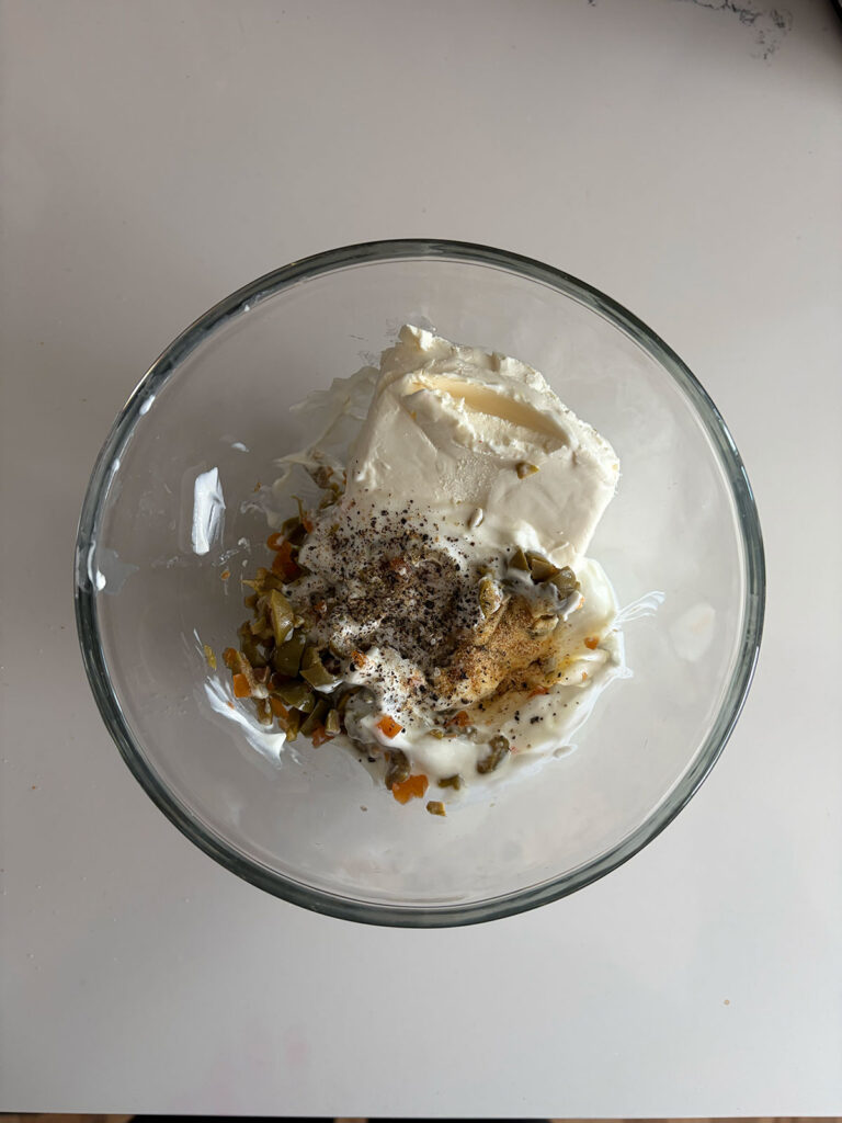 olive dip ingredients in clear bowl ready to be mixed