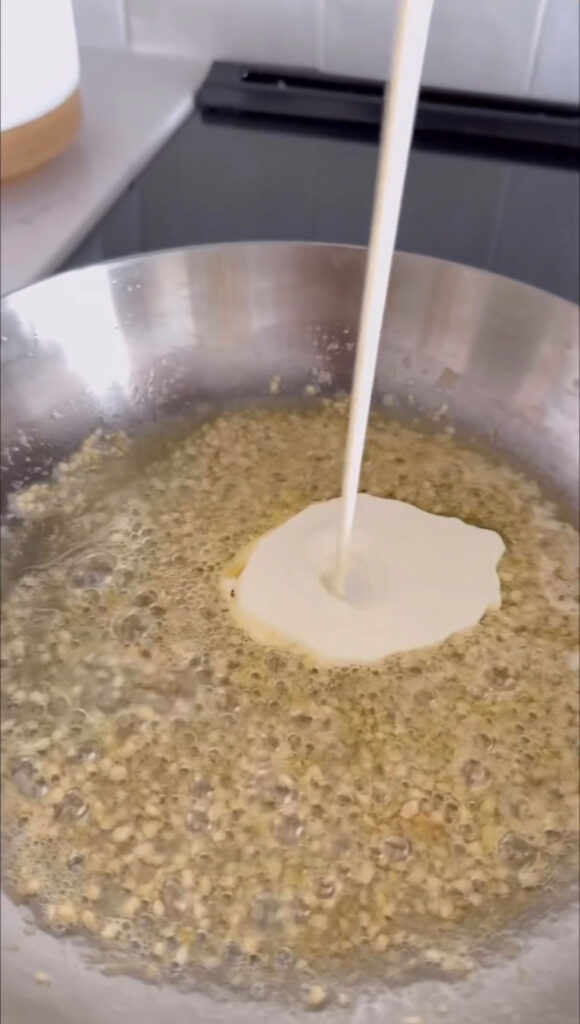 cream being added to garlic and butter in pan
