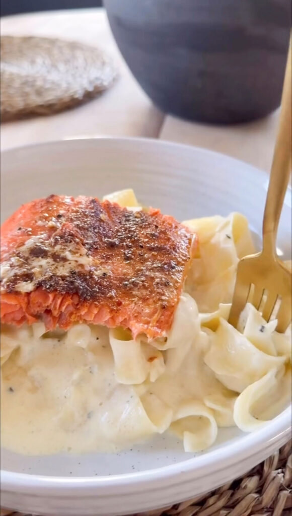 finished bowl of salmon alfredo in white bowl with gold fork