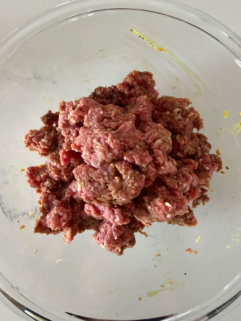 raw seasoned ground beef in clear bowl