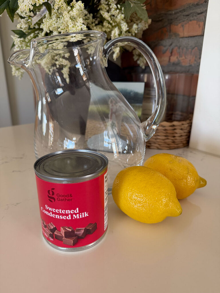 creamy lemonade ingredients on counter with vase of flowers in background