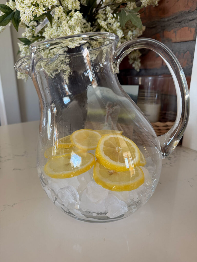 clear pitcher with ice and sliced lemons at the bottom