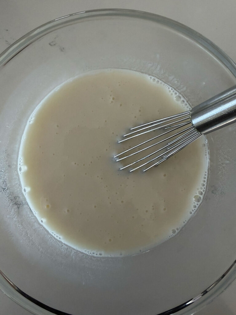 sweetened condensed milk and lemon juice in glass bowl with whisk