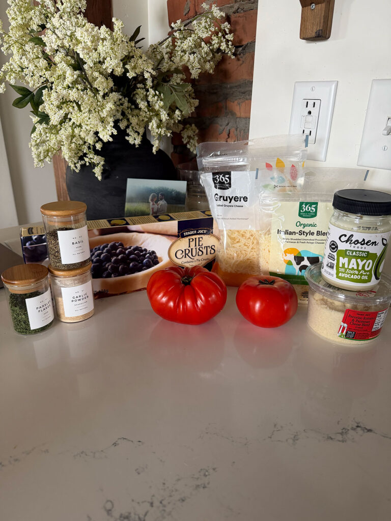 tomato pie ingredients on counter top with vase of flowers