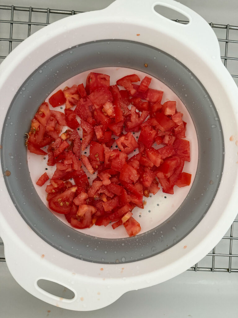 diced raw tomatoes in mixing bowl draining